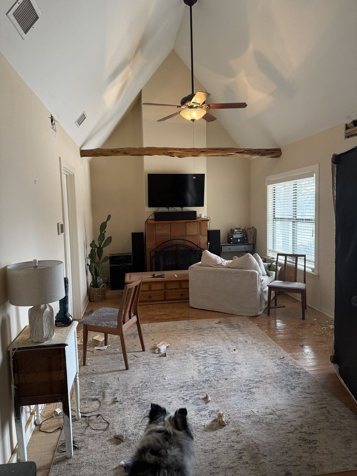 Living room before renovation with a low cedar beam crossing the vaulted ceiling and a ceiling fan.