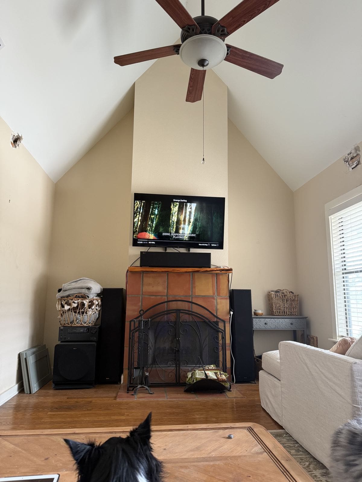 Fireplace flanked by blank walls with free-standing speakers on the floor before built-ins.