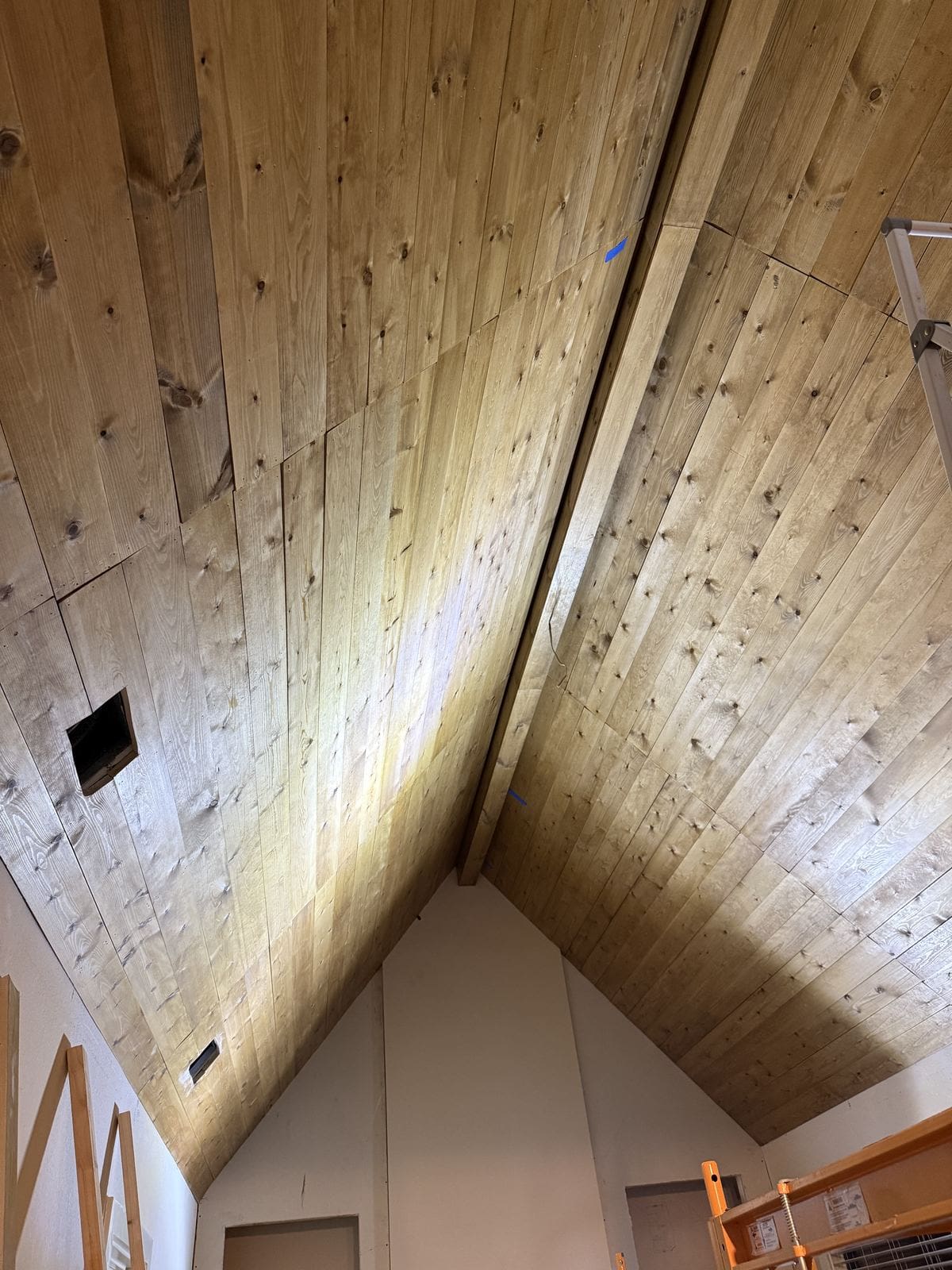 Raw pine planks installed across the vaulted ceiling before staining.