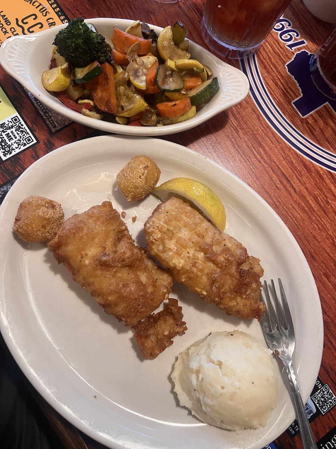 A fried fish plate with mashed potatoes and vegetables at Billy Gene
