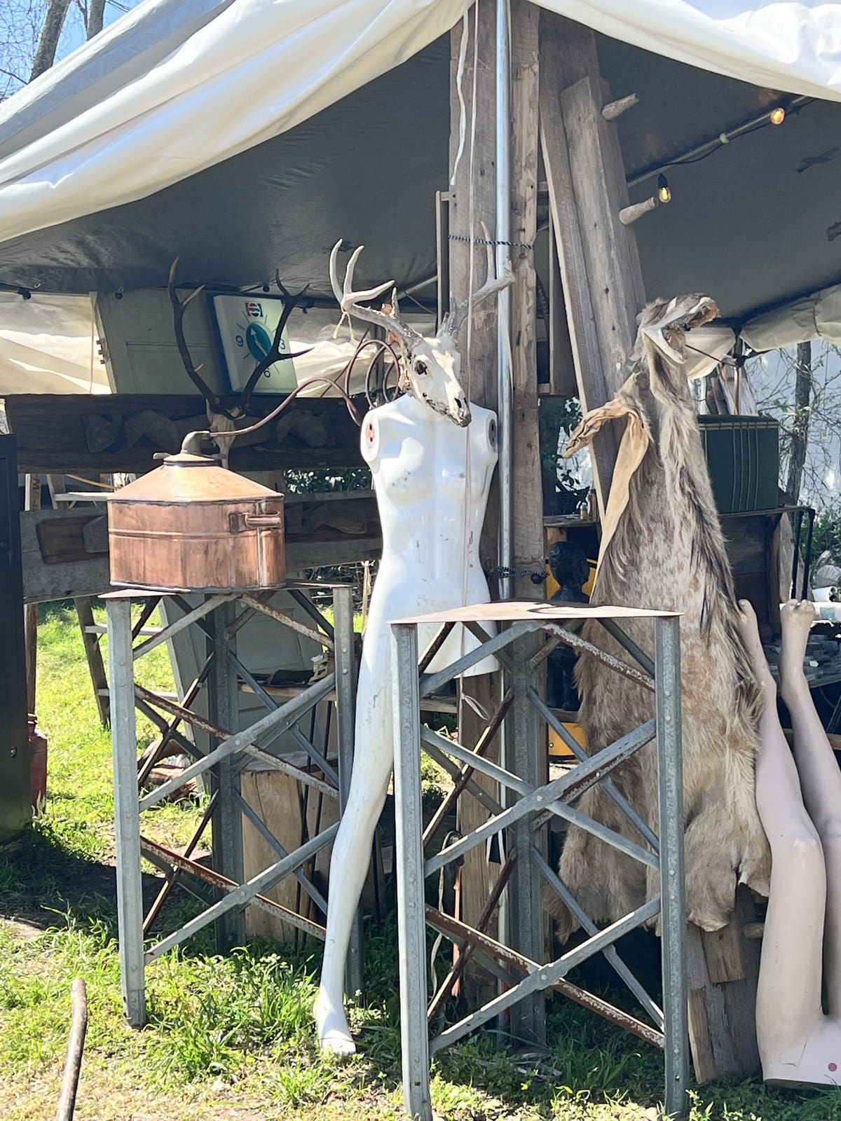 An antiques booth at Round Top with a dress form, copper vessels, and vintage finds