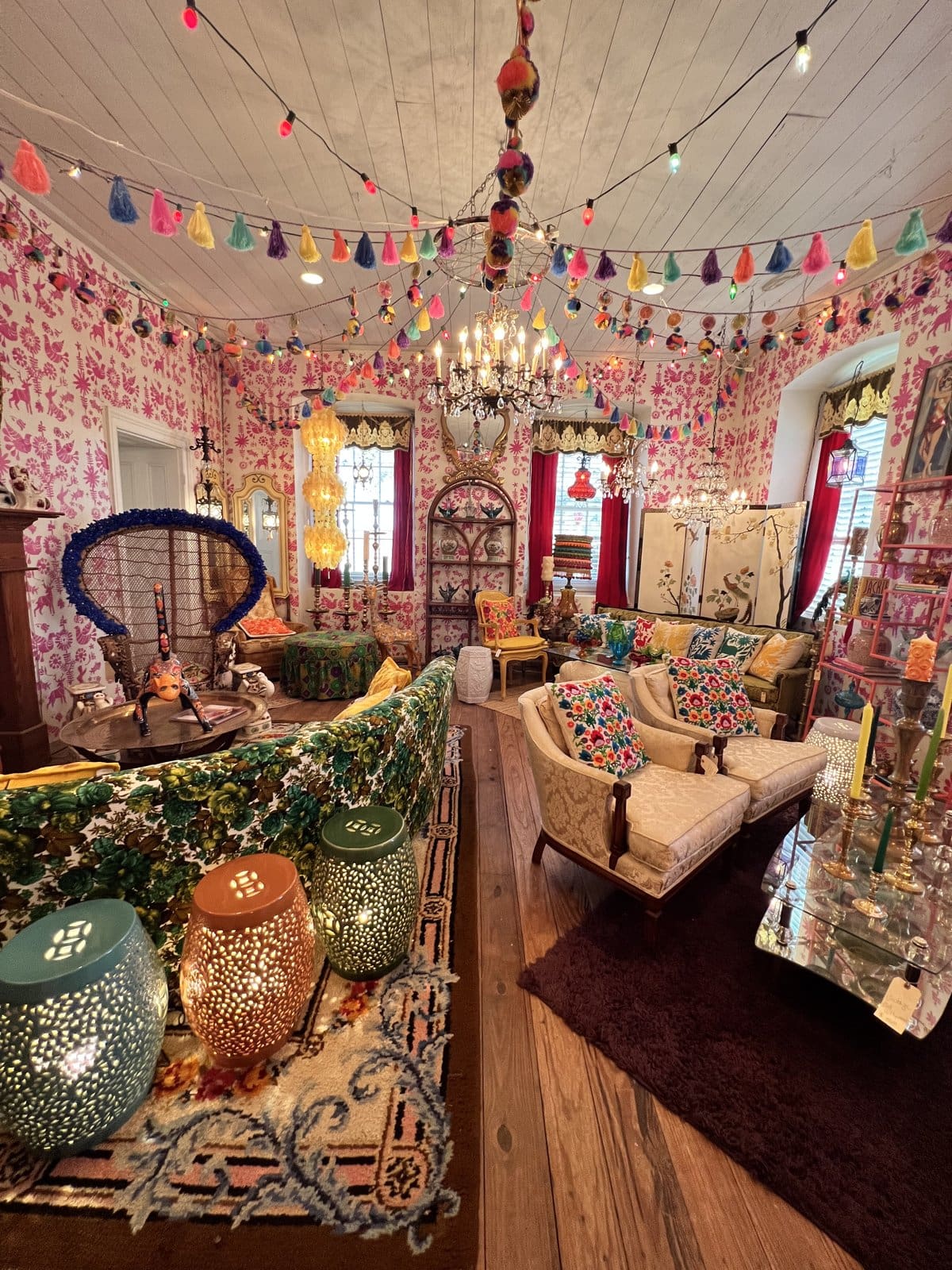 A colorful eclectic booth at Round Top antiques strung with bunting and hanging lanterns