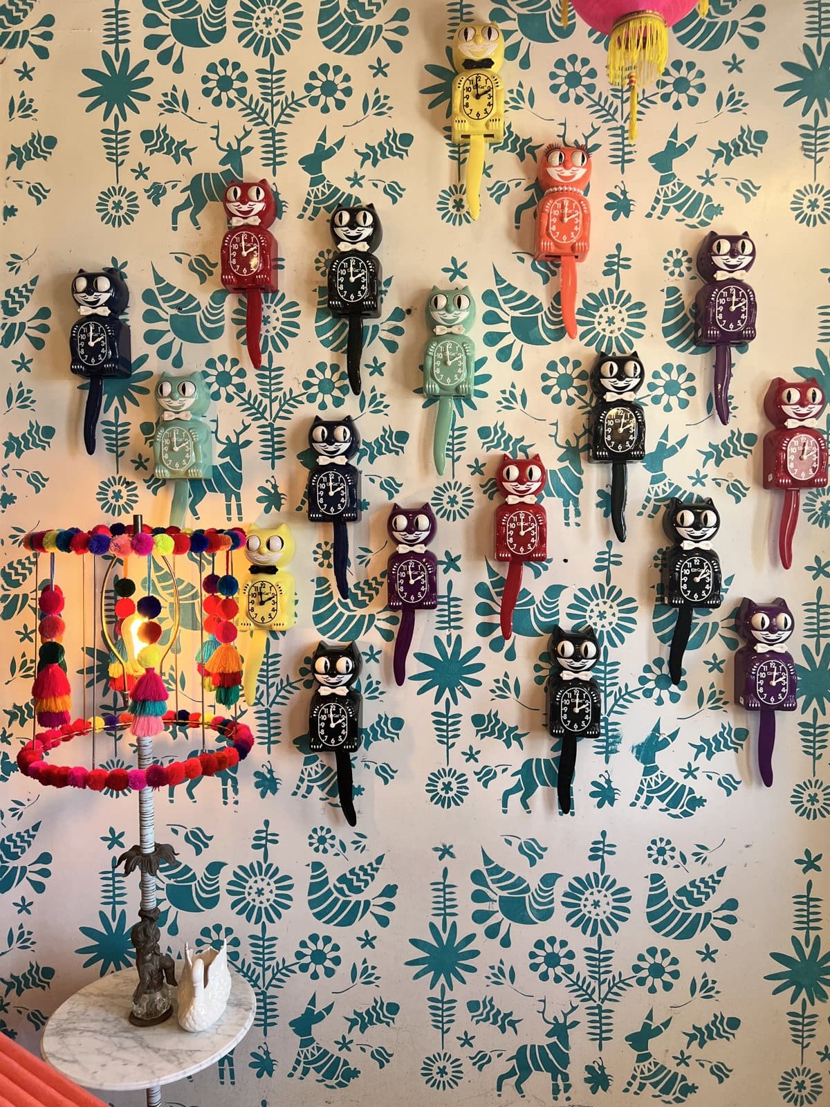 A wall of colorful folk-art figures on floral wallpaper at Round Top